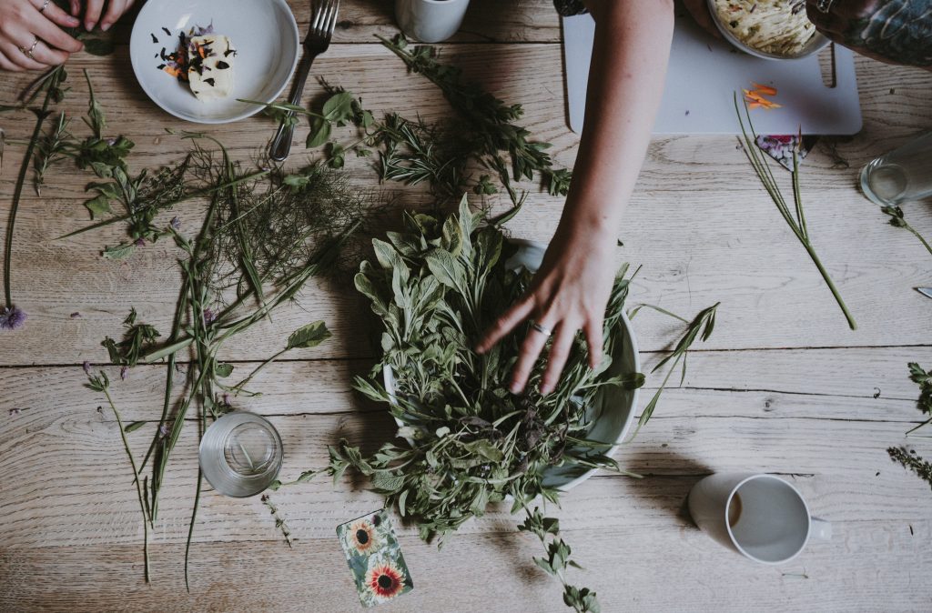 People sorting and preparing fresh herbs together on a wooden table.