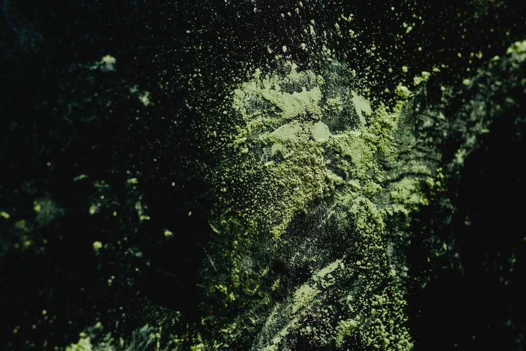 Green herbal powder spread across a dark surface.
