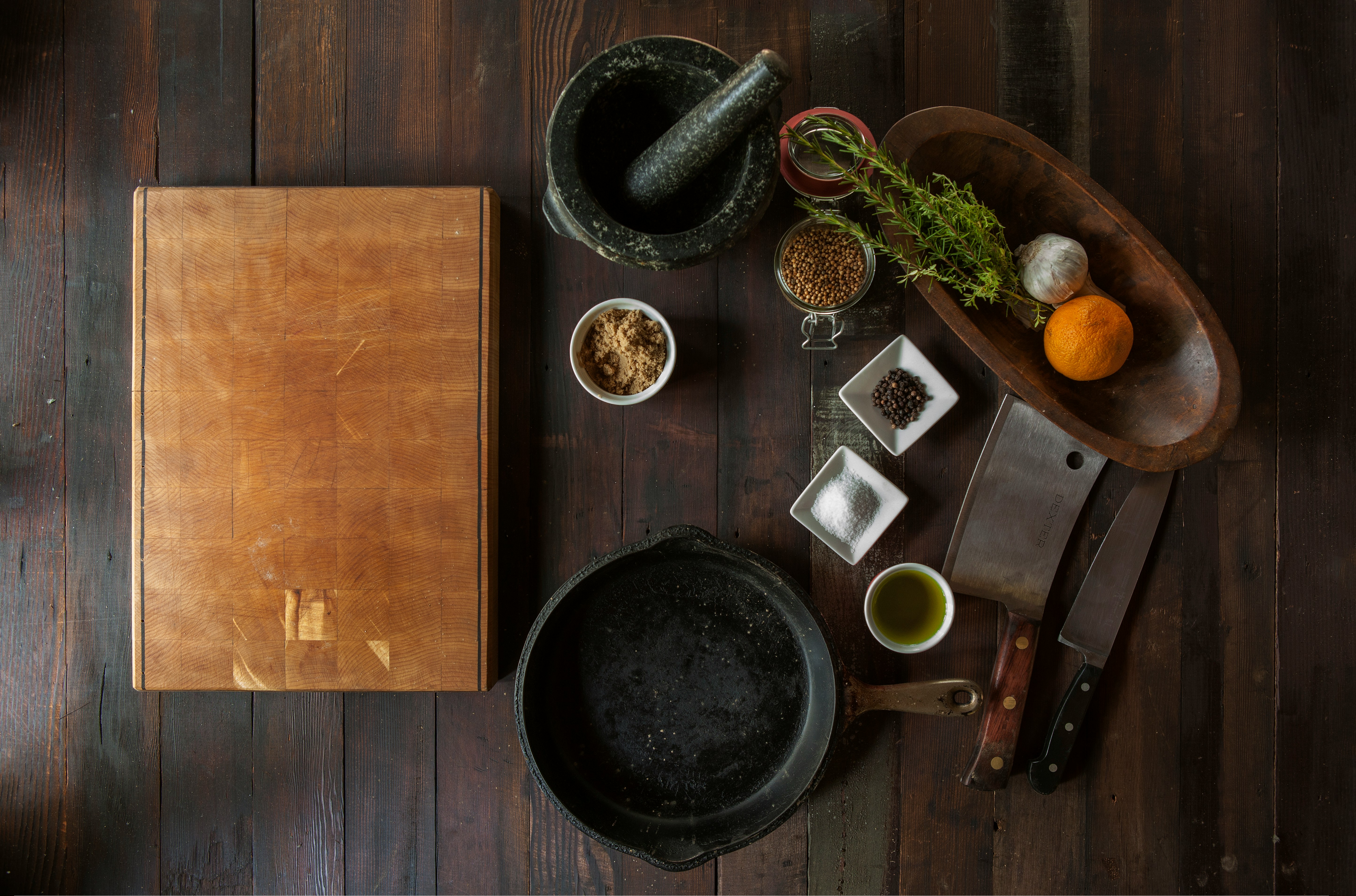Overhead view of culinary preparation tools and ingredients arranged on a wooden surface.